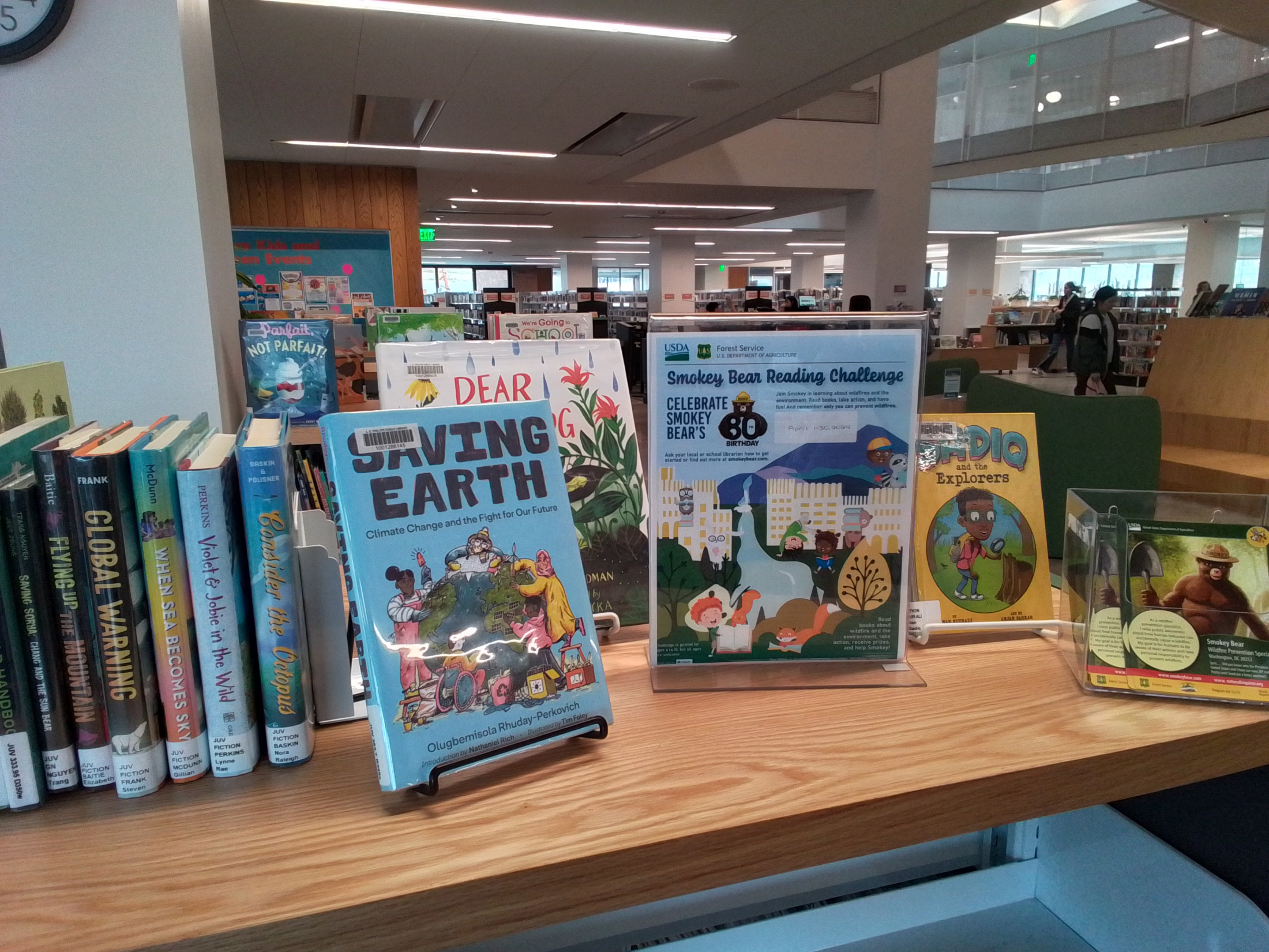 Picture of book display with earth and environmental related stories, and a Smokey Bear Reading Challenge sign.