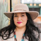 A woman of Native American descent with black hair and a round face, wearing a wide-brimmed hat.