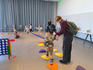 Child holding adults hand while doing obstacle course.