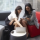 Two Businesswomen Using Laptop In Lobby Of Modern Office