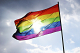 Photo of a Pride Flag against a beautiful blue sky.