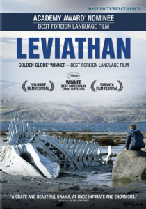 Cover art for film Leviathan, depicts a skeleton of a whale on a rocky beach. A person is perched on a rock to the right of the skeleton and looks out over a body of water with small rolling hills in the background. 